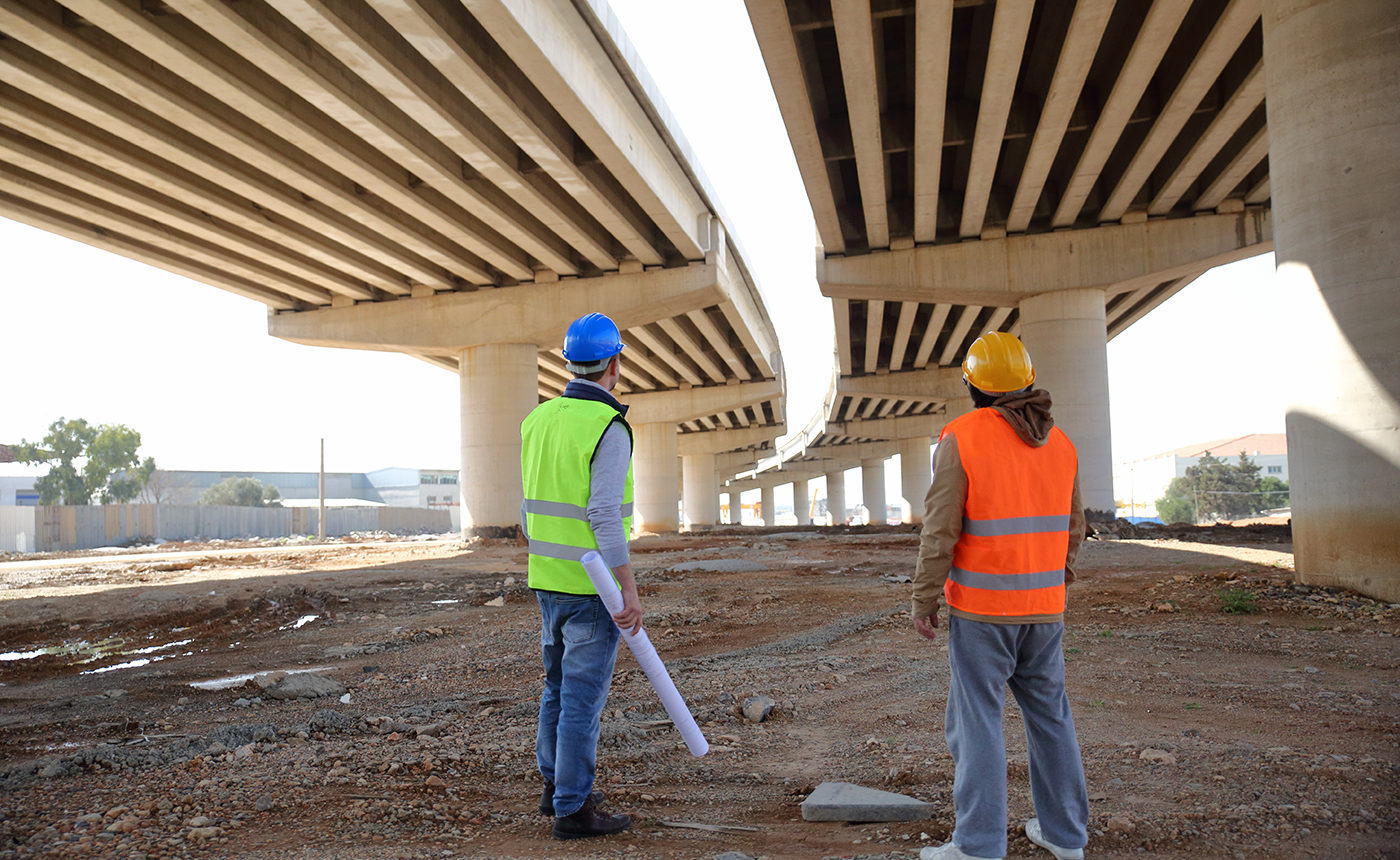 Two men looking up at the underside of a bridge - coating inspection