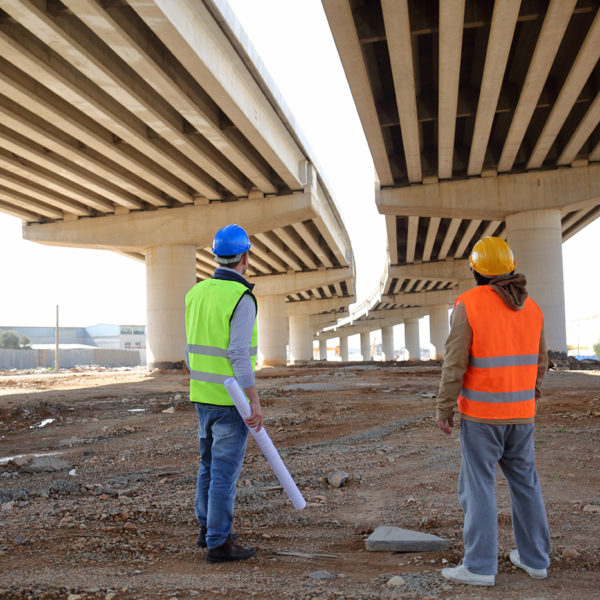 Two men looking up at the underside of a bridge - coating inspection